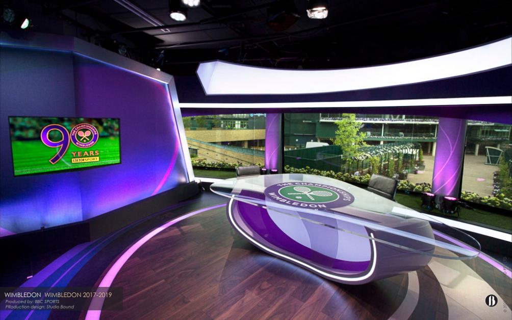 BBC Sport's Wimbledon studio (2017–2019) — the championship desk staged against The Championships' "90 Years" branding and a window onto the grounds. Production design by Patrick Larsen.