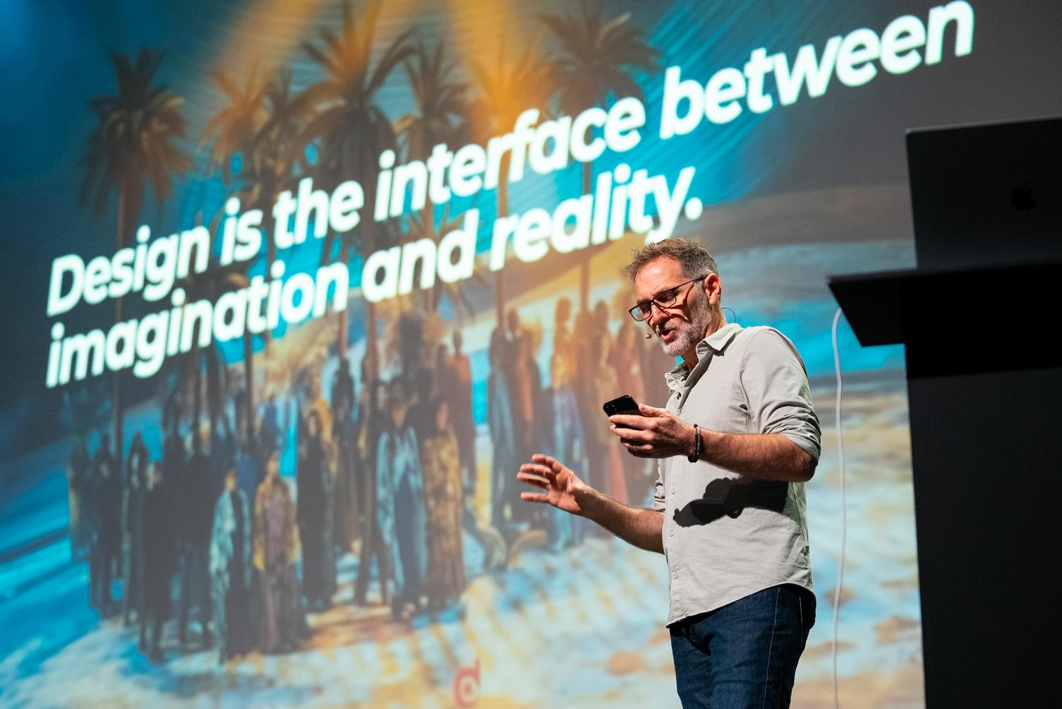 Patrick Larsen on stage in front of a slide reading "Design is the interface between imagination and reality."