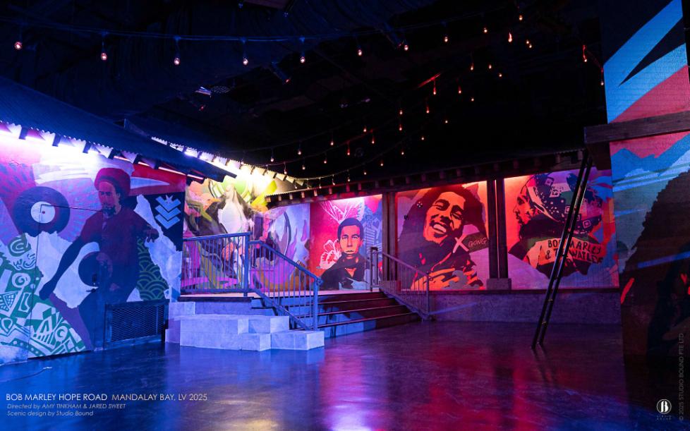 The Hope Road corridor — a mural-lined street the audience walks before the first room opens, setting the visual grammar of the whole experience in spray-paint and warm Edison lights. Scenic design by Studio Bound.