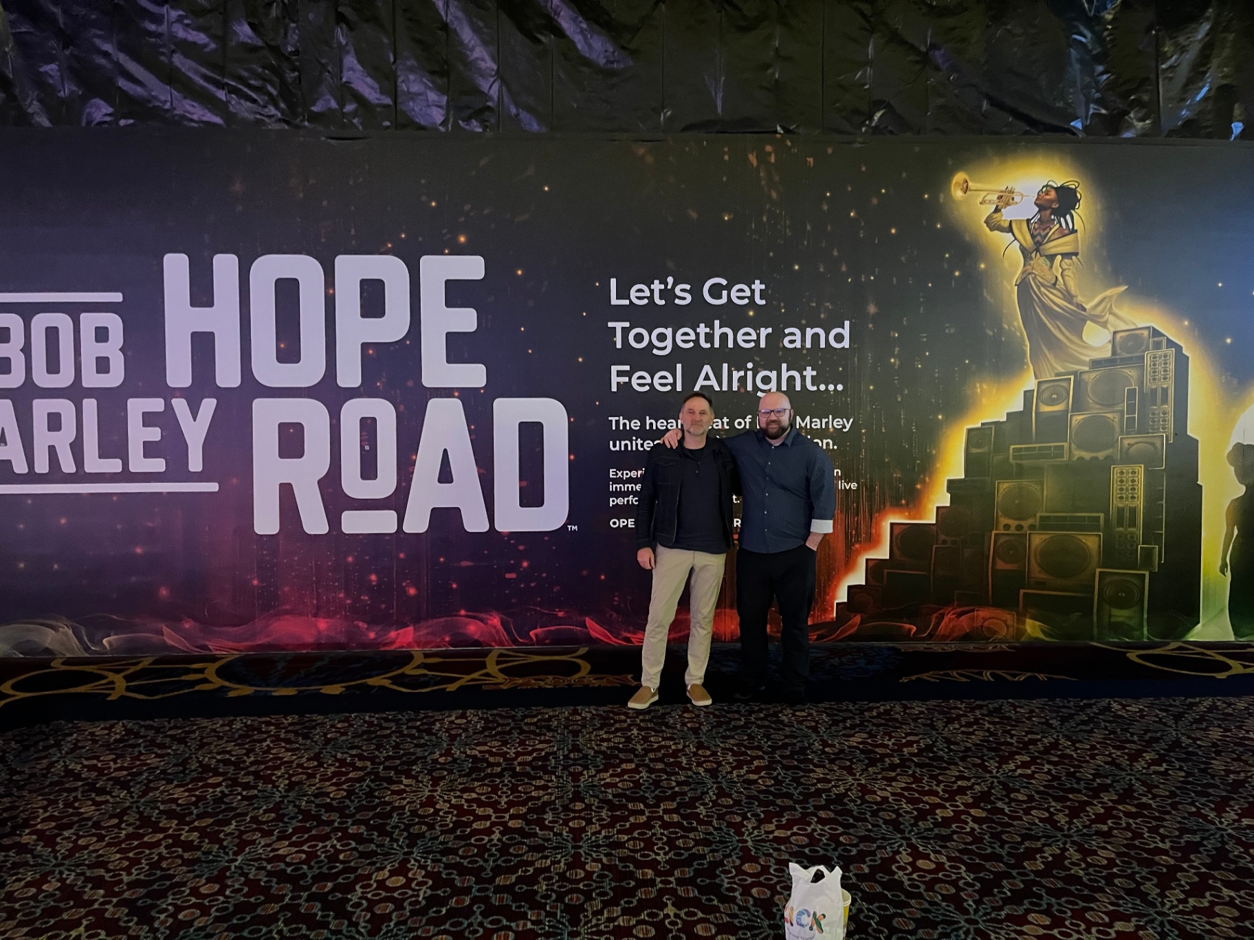 Patrick Larsen standing in front of the Bob Marley: Hope Road immersive experience wall.
