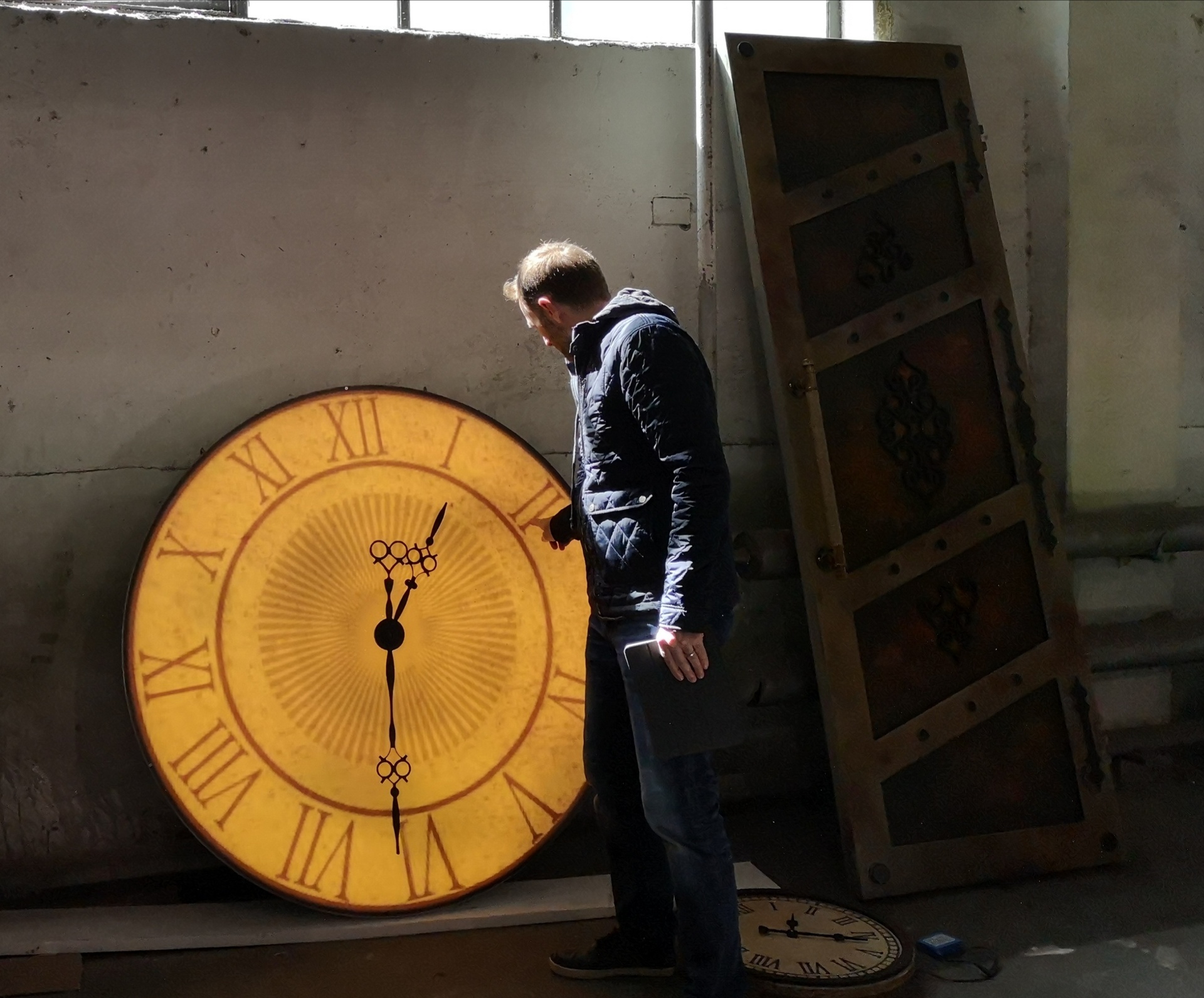Patrick Larsen next to a giant illuminated clock face in a Studio Bound workshop.